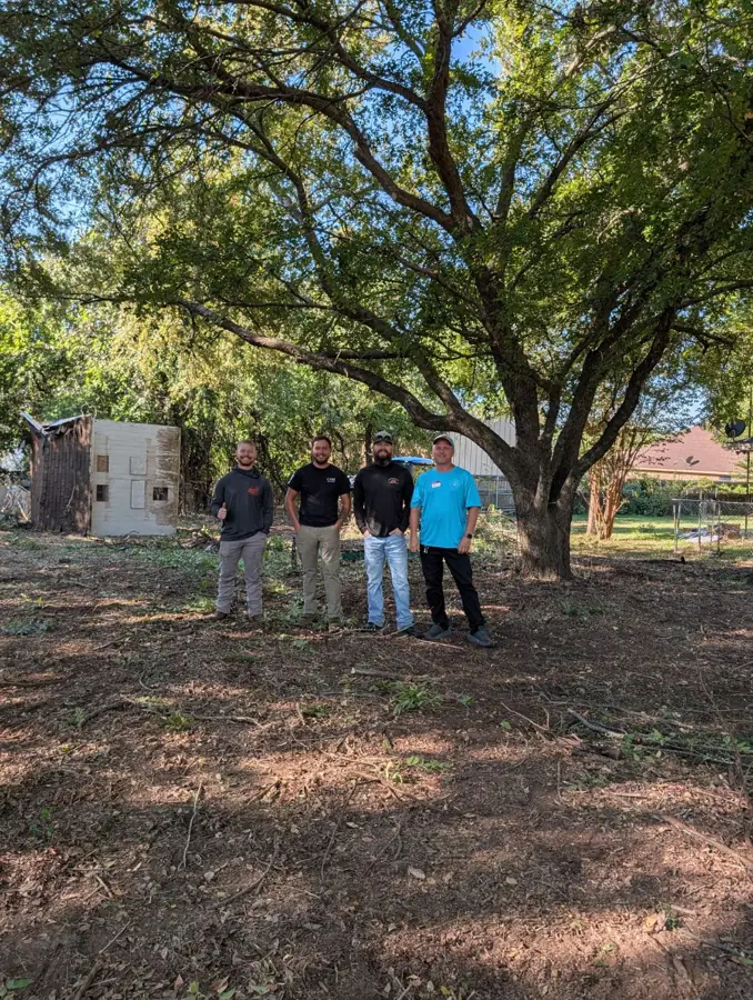 Four participating crew members beneath a tree at the community work event
