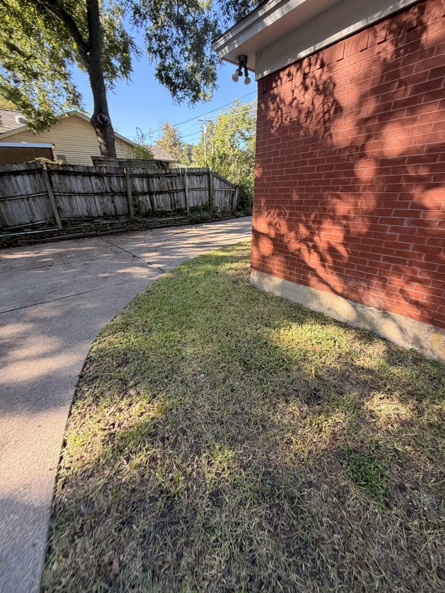 Mowed grass alongside a curved driveway and brick house in Weatherford, Texas.